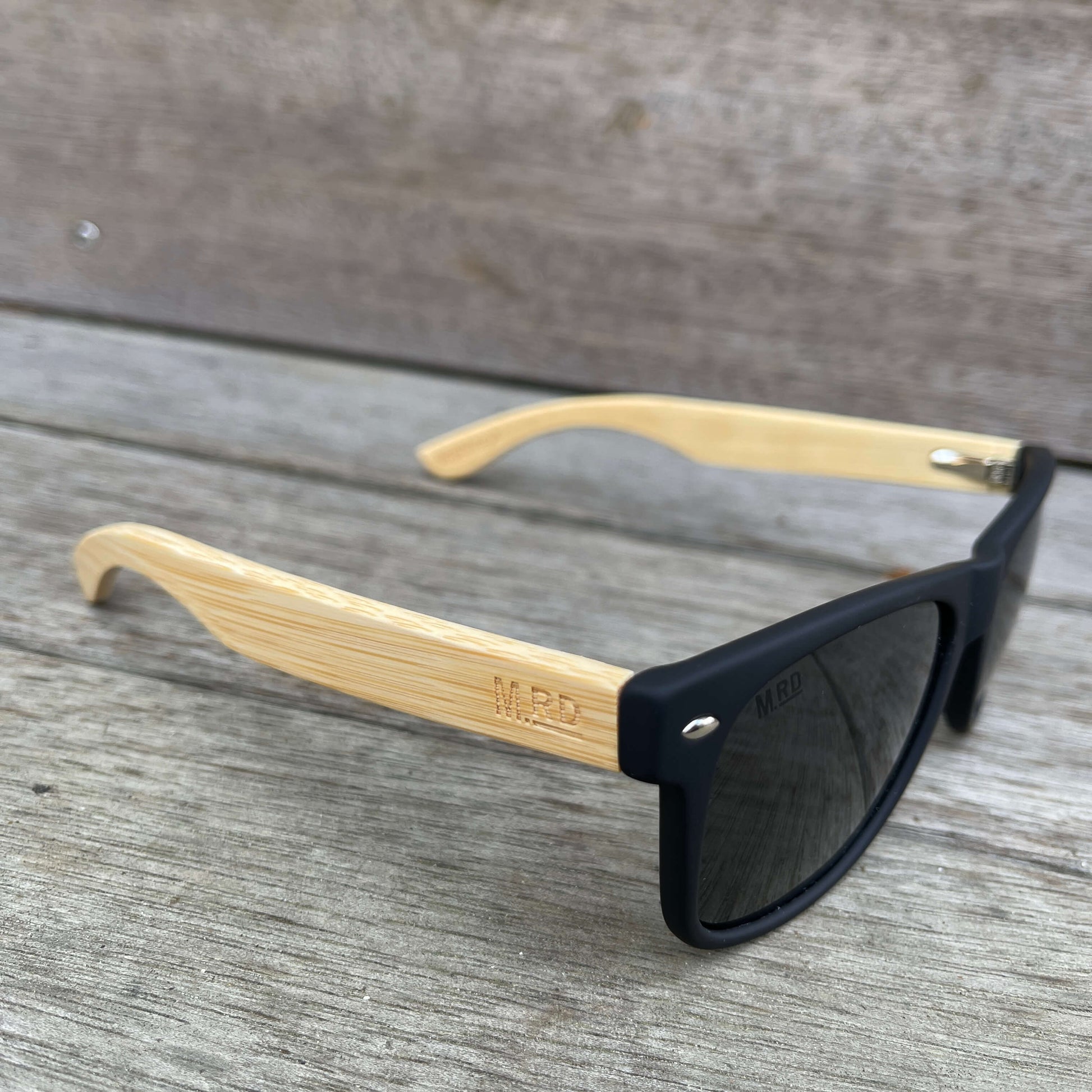 Sunglasses with wooden arms, black frames and dark lenses.