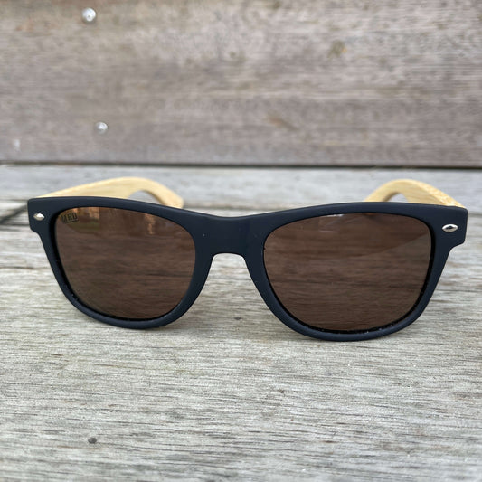 Sunglasses with wooden arms, black frames and brown lenses.