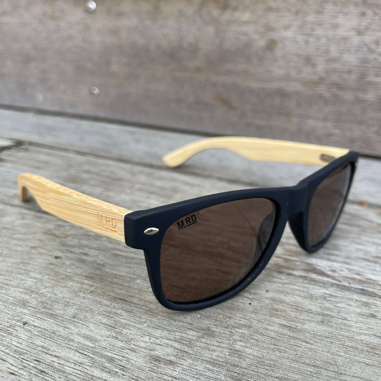 Sunglasses with wooden arms, black frames and brown lenses.