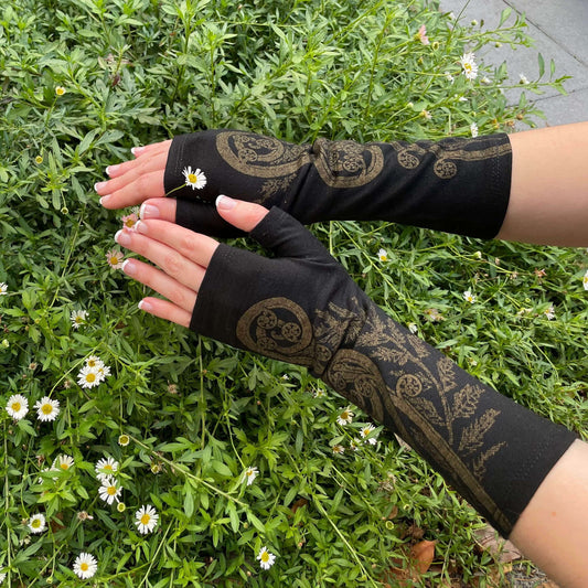 Fingerless merino gloves in black with gold fern print.
