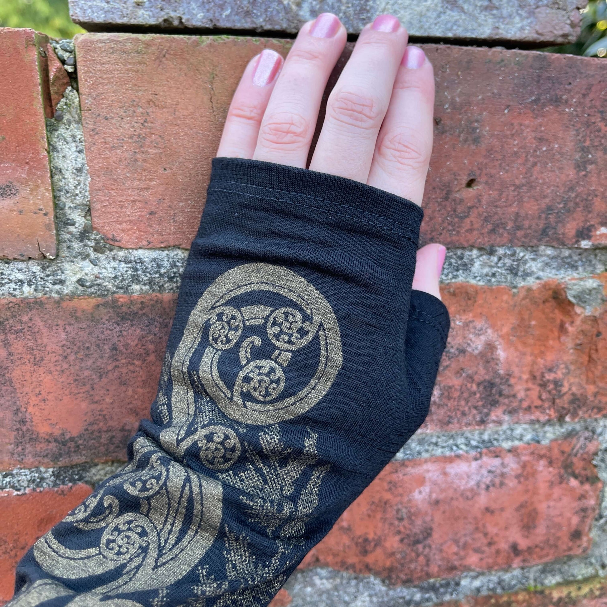 Fingerless merino gloves in black with gold fern print.
