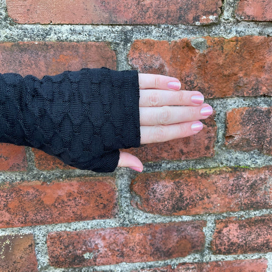 Fingerless merino gloves in textured black knit.