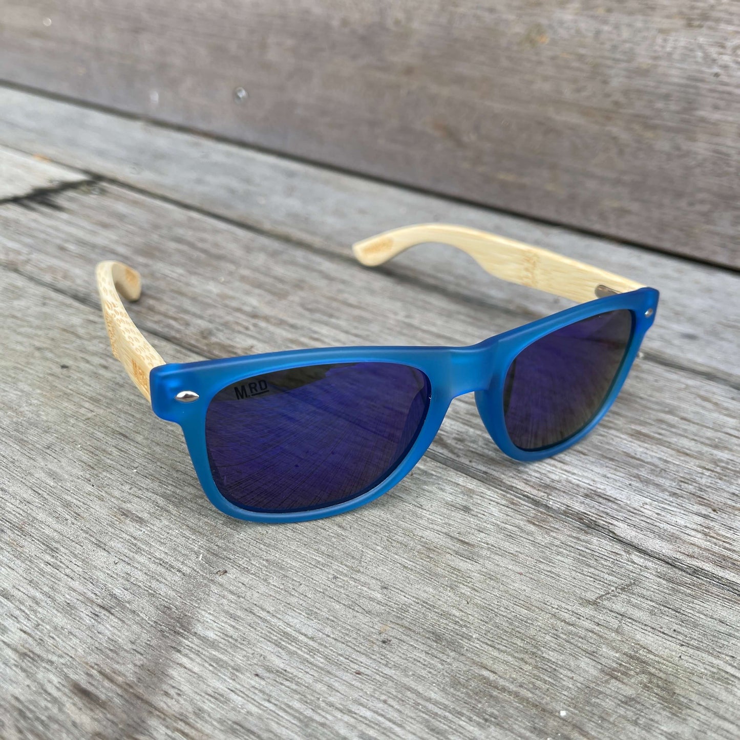 Sunglasses with wooden arms, blue frames and blue reflective lenses.