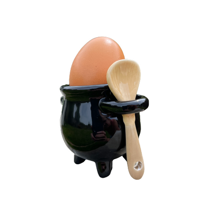 Black ceramic cauldron shaped egg cup with ceramic broom spoon.