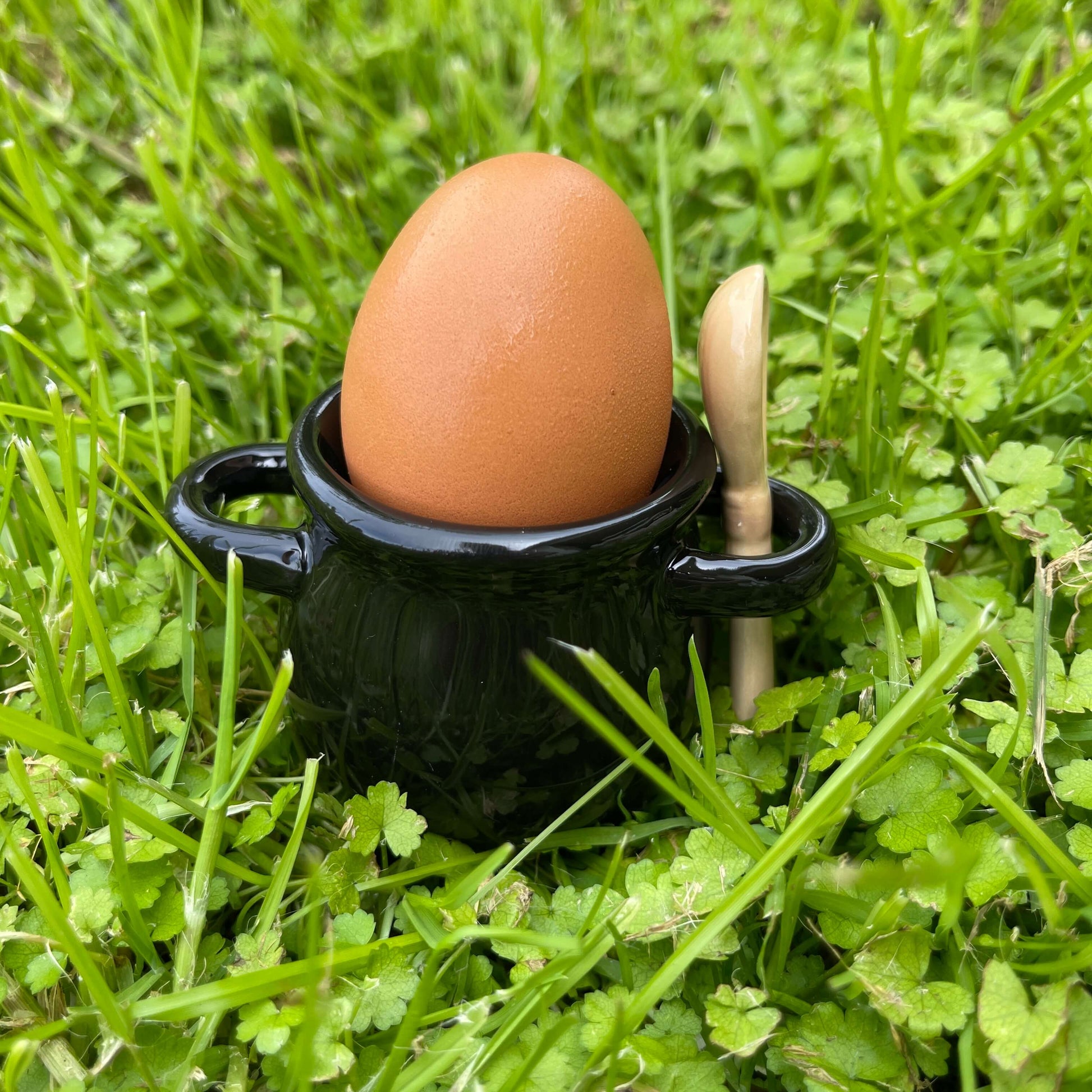 Black ceramic cauldron shaped egg cup with ceramic broom spoon.