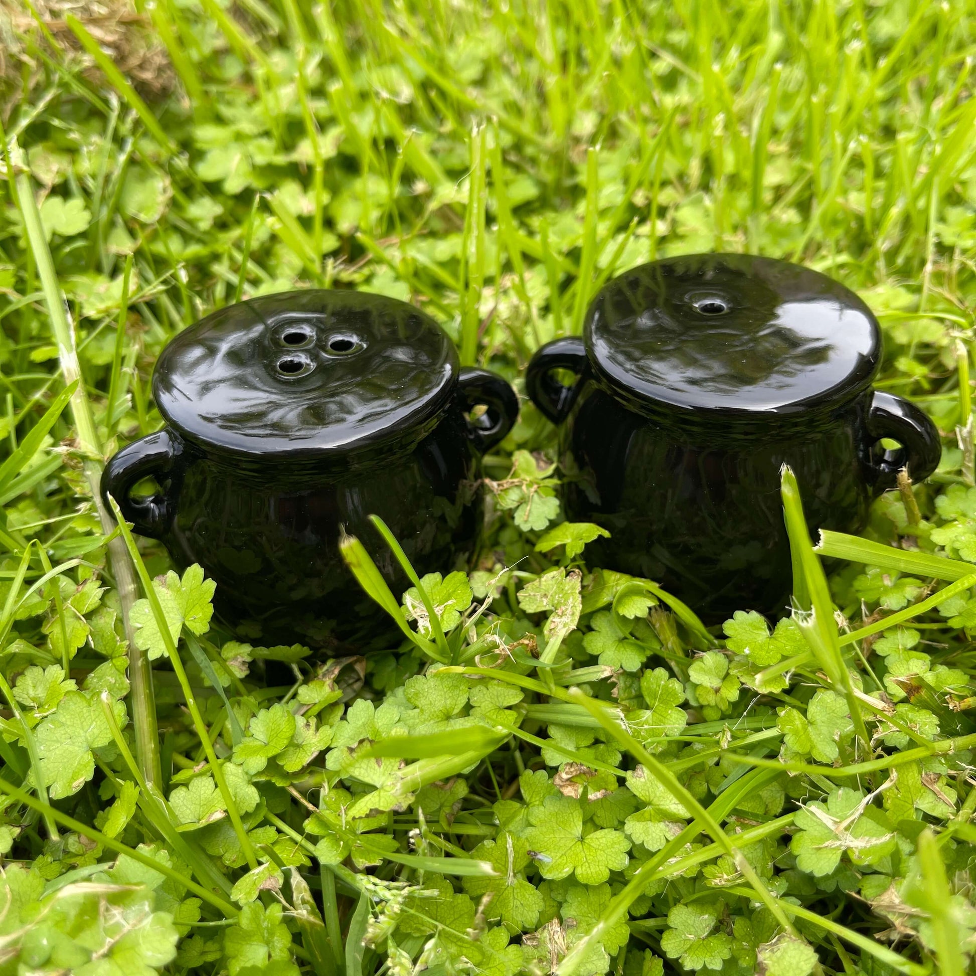 Black ceramic cauldron shaped salt and pepper shaker set.