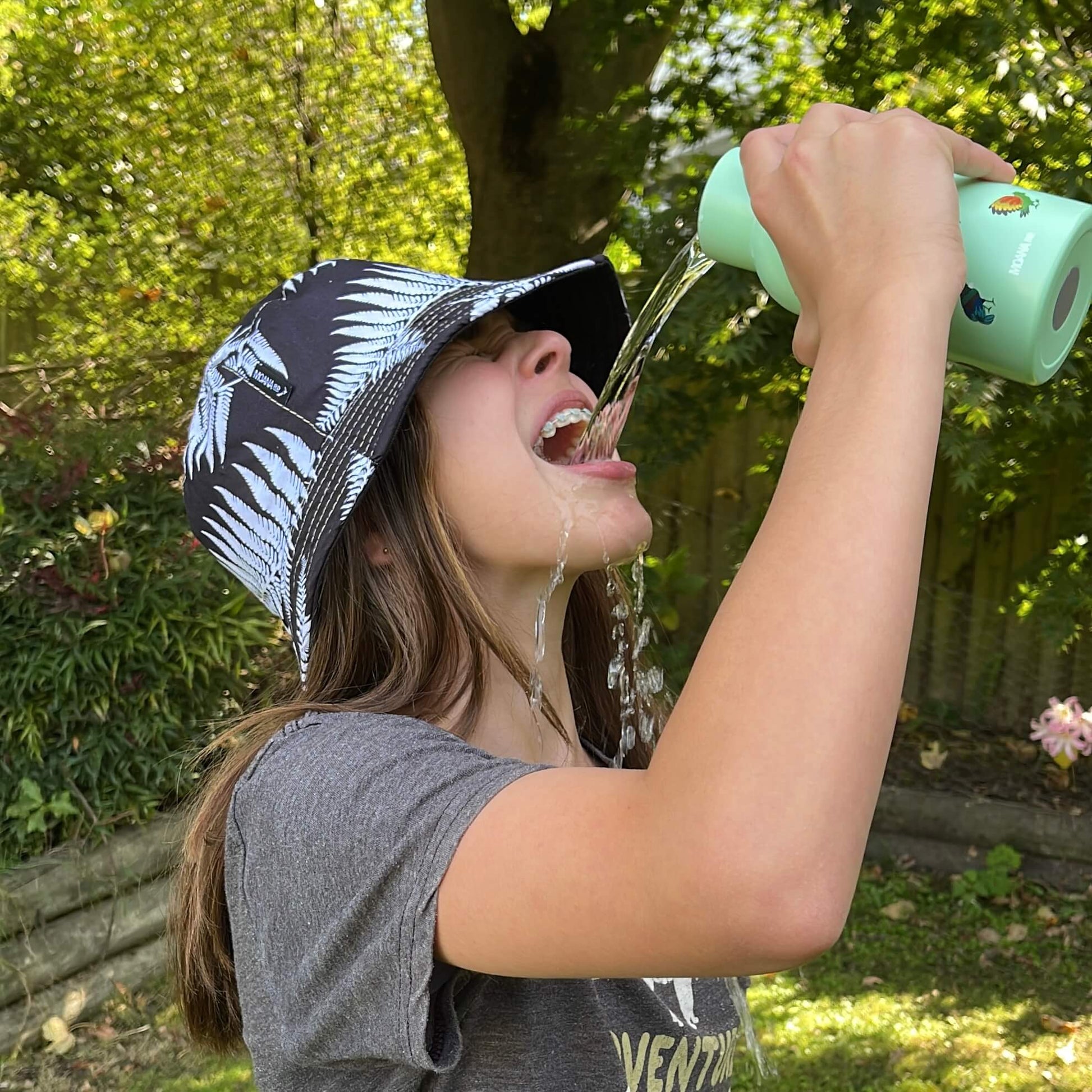 Young girl pouring water from a drink bottle into her mouth.