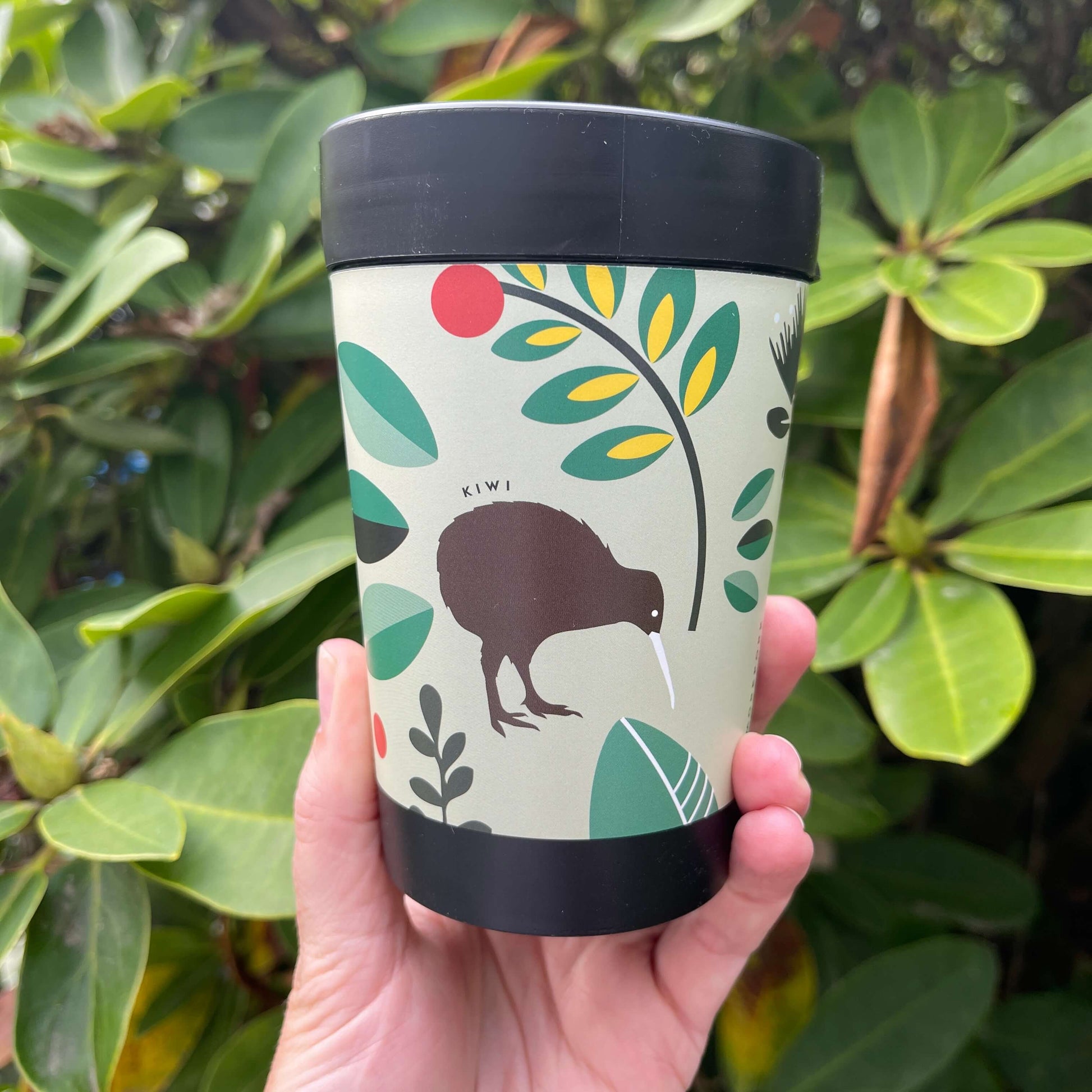 Black reusable coffee cup featuring New Zealand birds in a cartoon style on a minty green wrap background.
