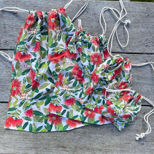 Four different sized drawstring bags in a Pohutukawa flower print.
