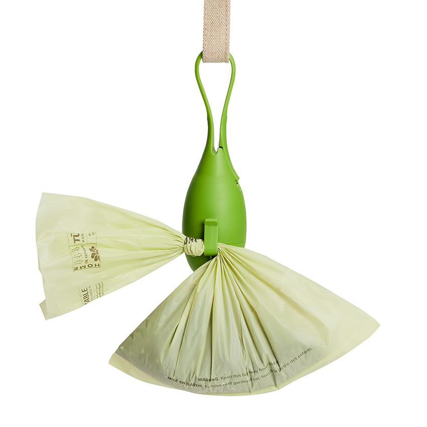 Bright green silicone tea drop shaped dog poo bag dispenser showing how a full bag hooks into the holder at the bag before disposale.