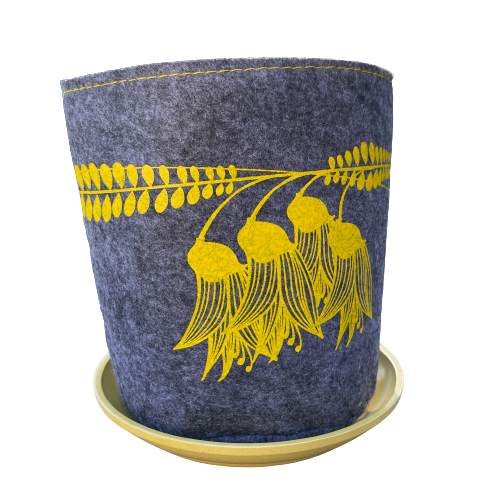 Grey felt planter with yellow kowhai flowers printed on it and sitting in a yellow dish.