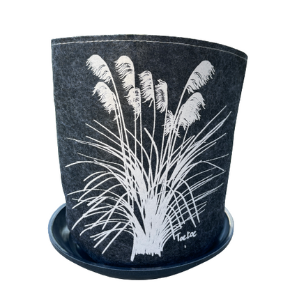 Dark grey felt planter with white toetoe plant printed on it sitting in a grey saucer.