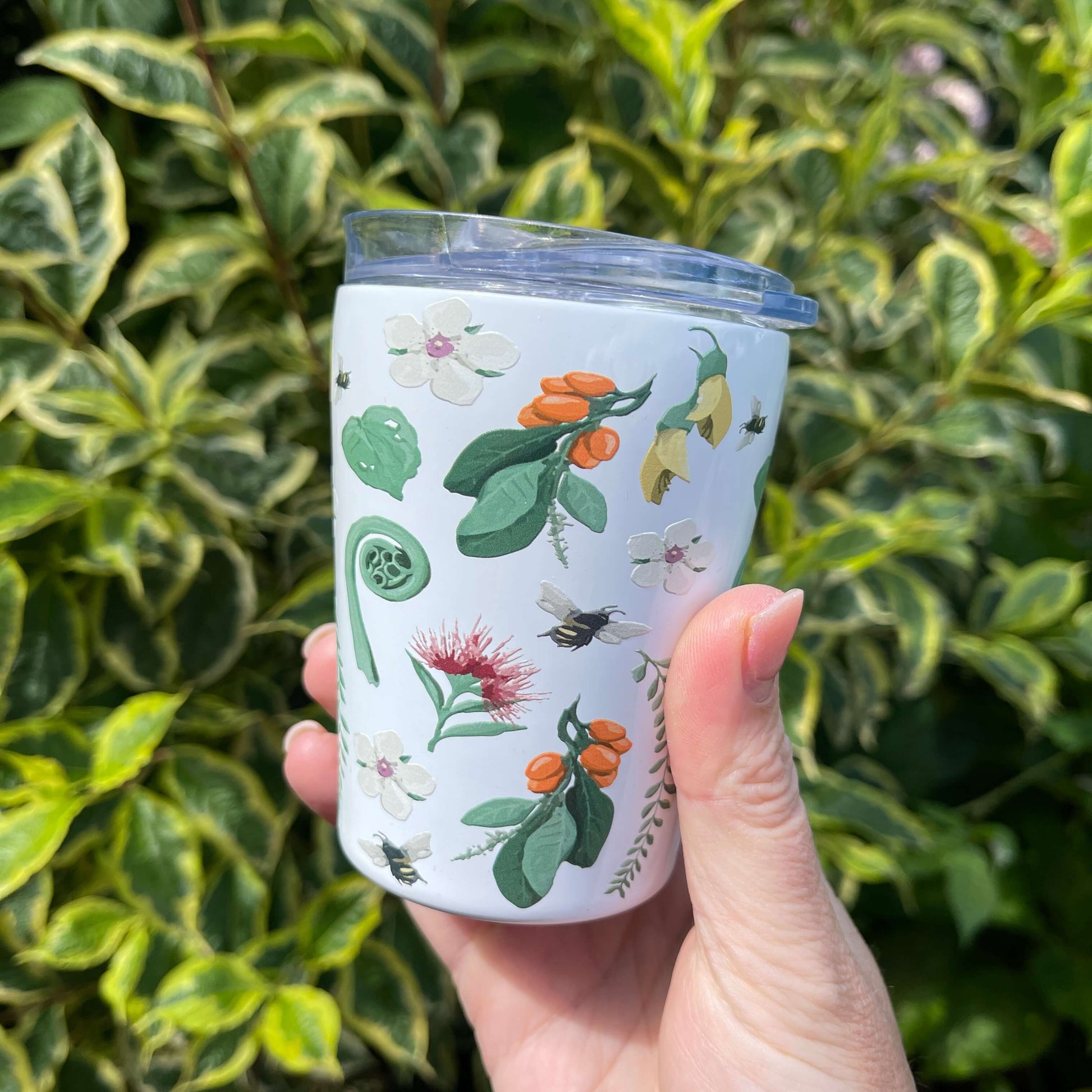 White reusable coffee mug with native New Zealand flora and fauna print.
