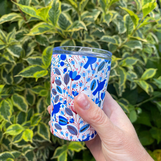 Small reusable coffee cup in white with a blue and red Tui bird and floral design.