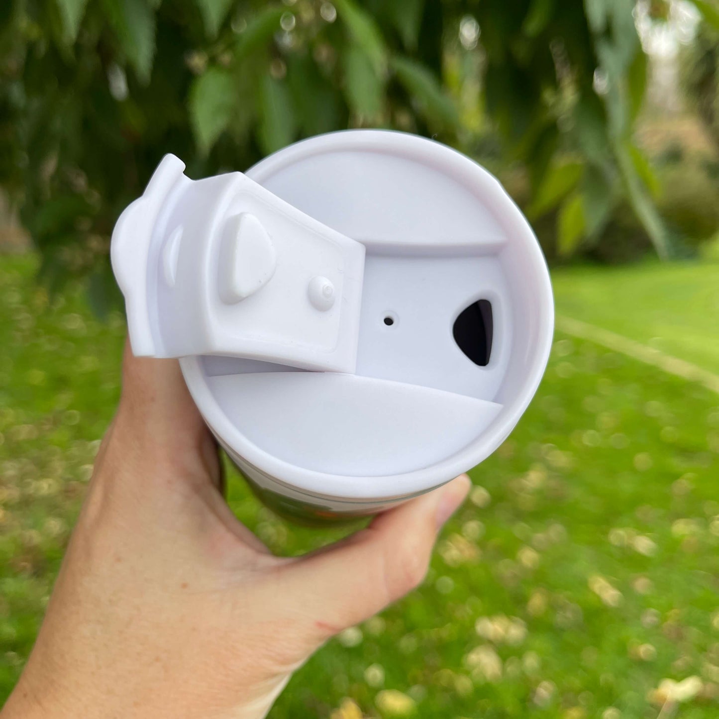 Birds eye view of an open white plastic sipper top for a reusable cup.