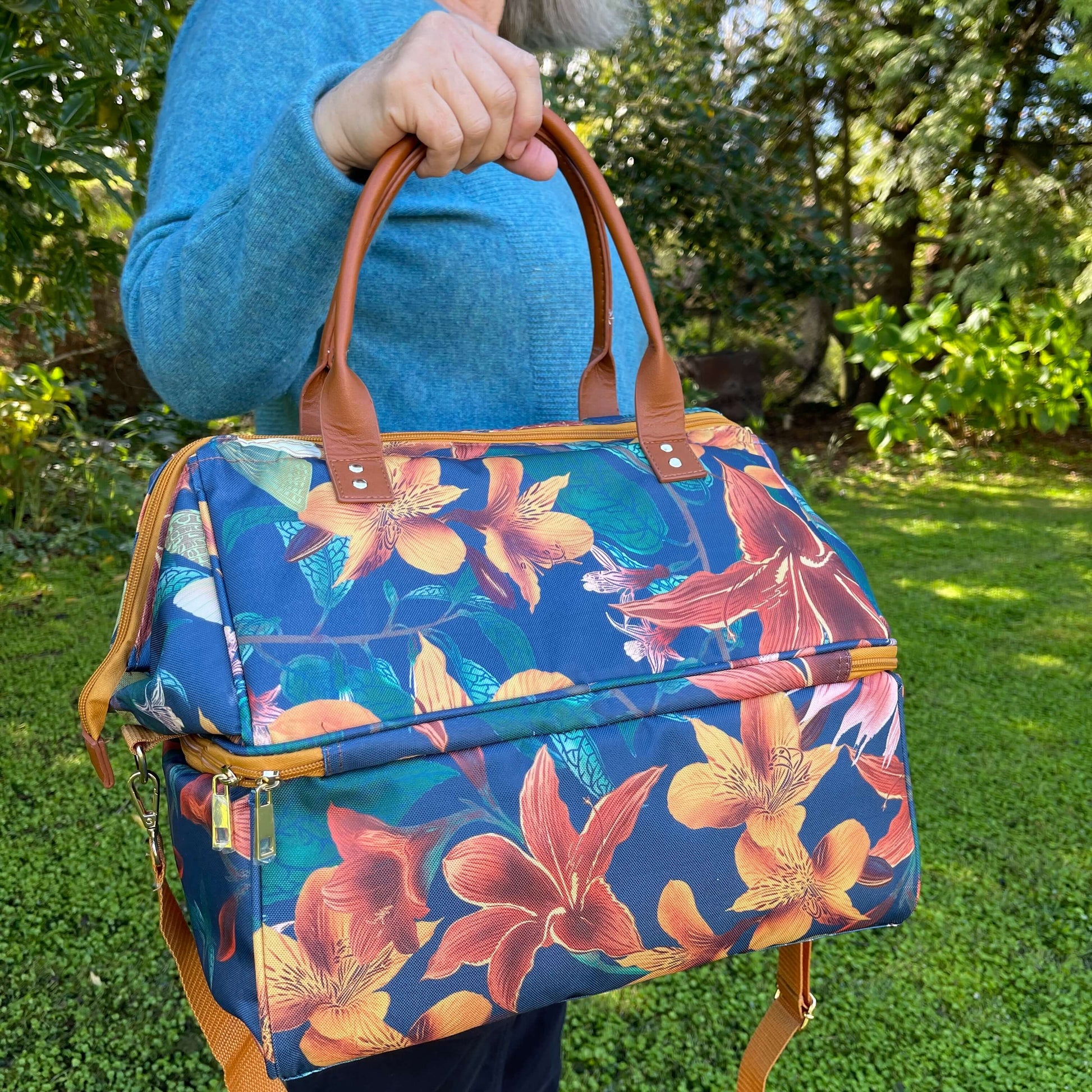 Women holding a large cooler bag which is a navy blue with orange flowers.