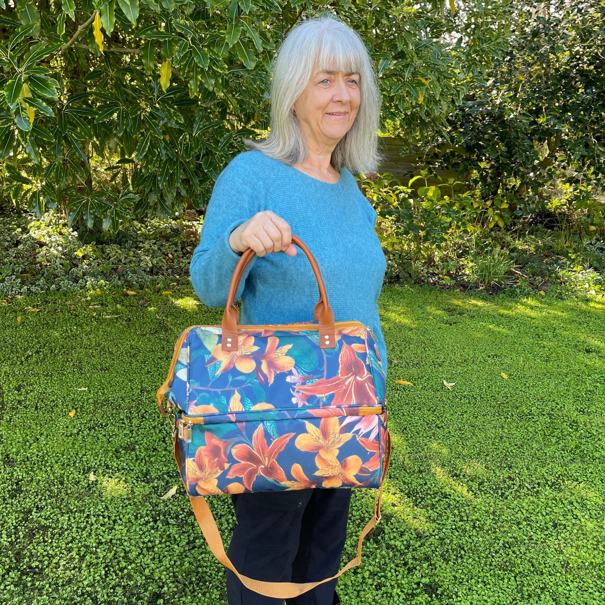 Women holding a large cooler bag which is a navy blue with orange flowers.