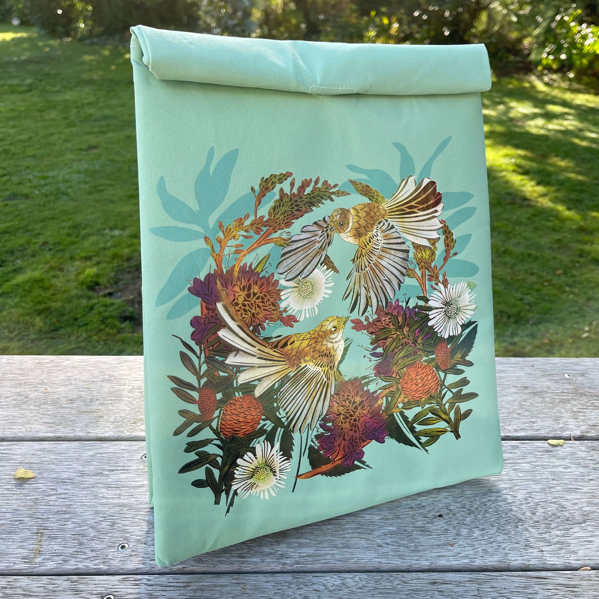 Light blue folding paper style lunch bag with floral and bird design.