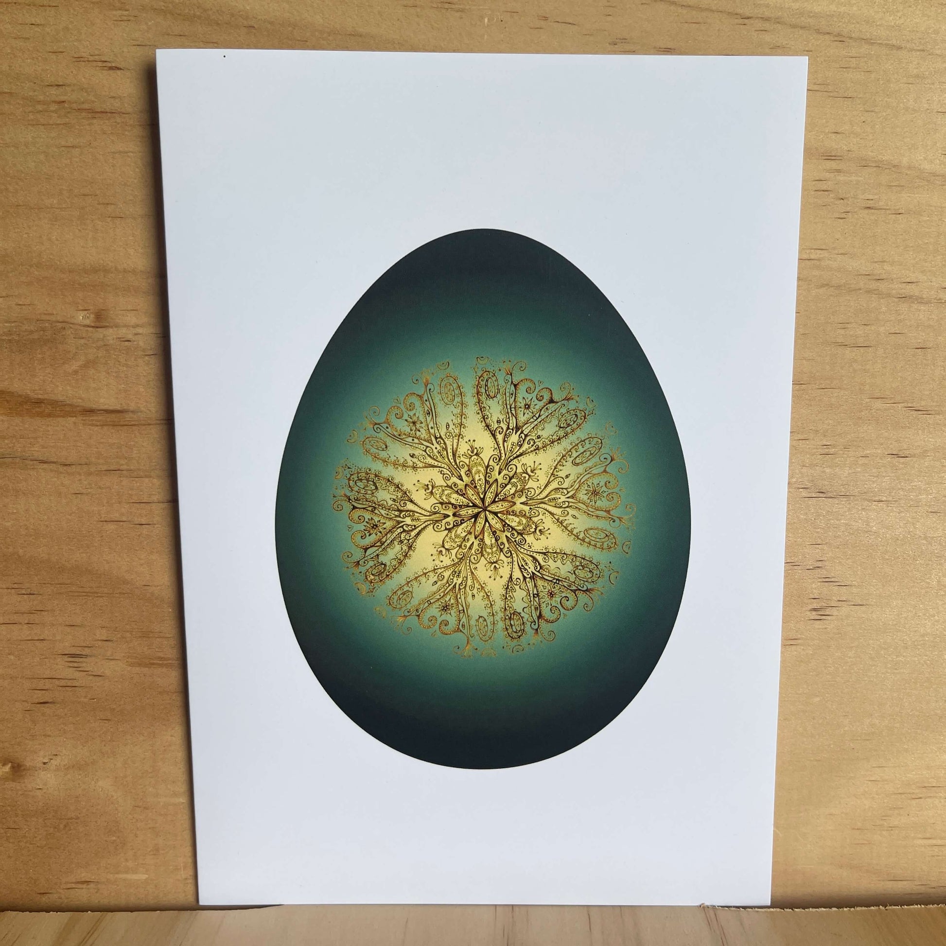 Greeting card with greenstone themed egg and gold vine pattern inside egg. 