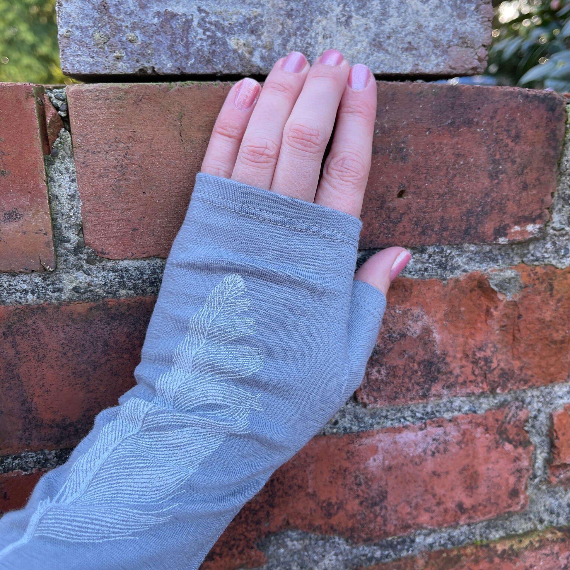 Fingerless merino gloves in light grey with white feather print.