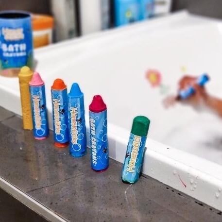 Bath crayons by Honey Sticks on the side of a bath.