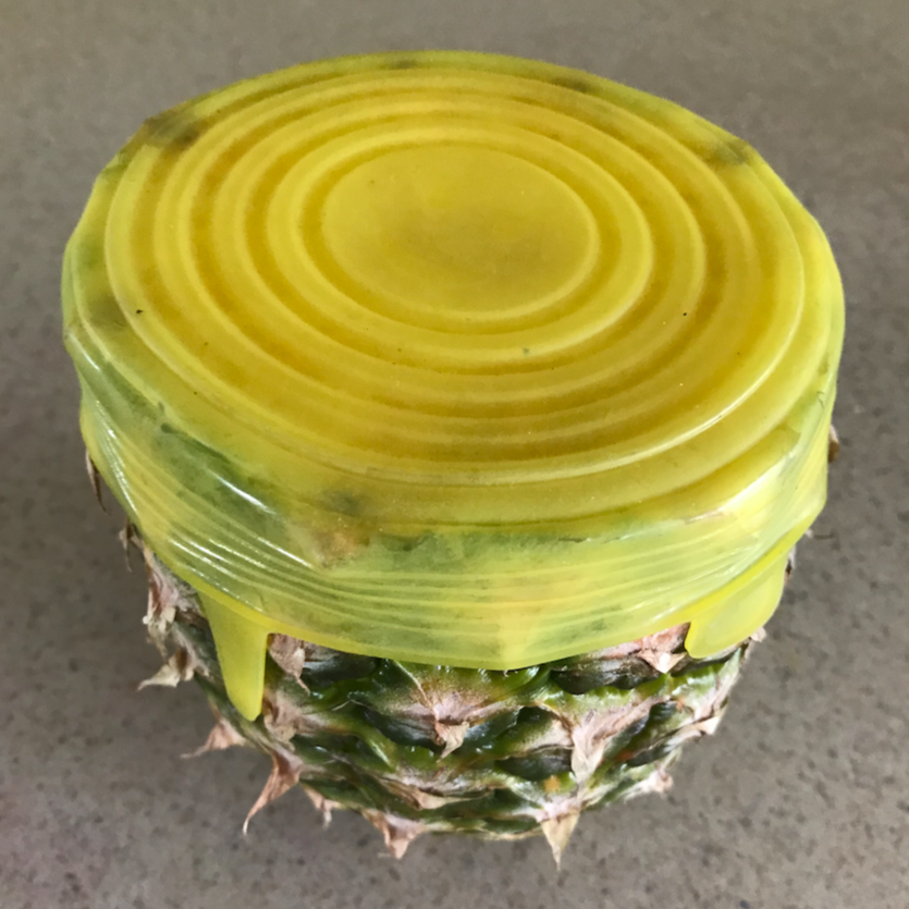 Half a pineapple with a silicone stretch lid covering the cut end.