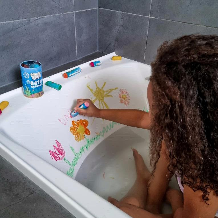 Child in a bath playing with bath crayons.