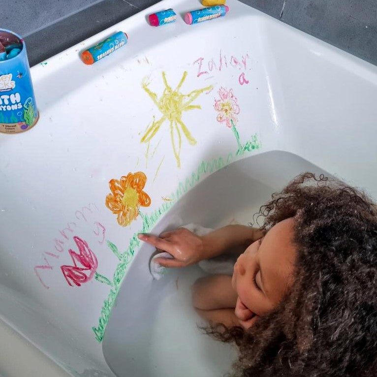 Child in a bath playing with bath crayons.