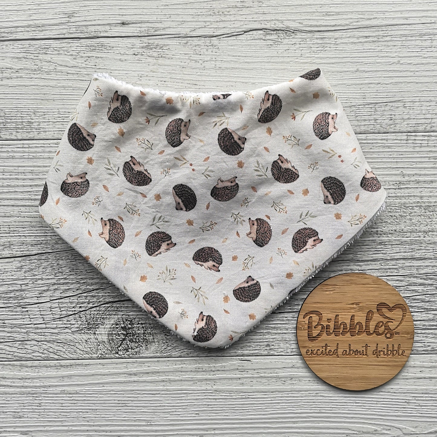 Babies dribble bib with a cute hedgehog print on a cream background.