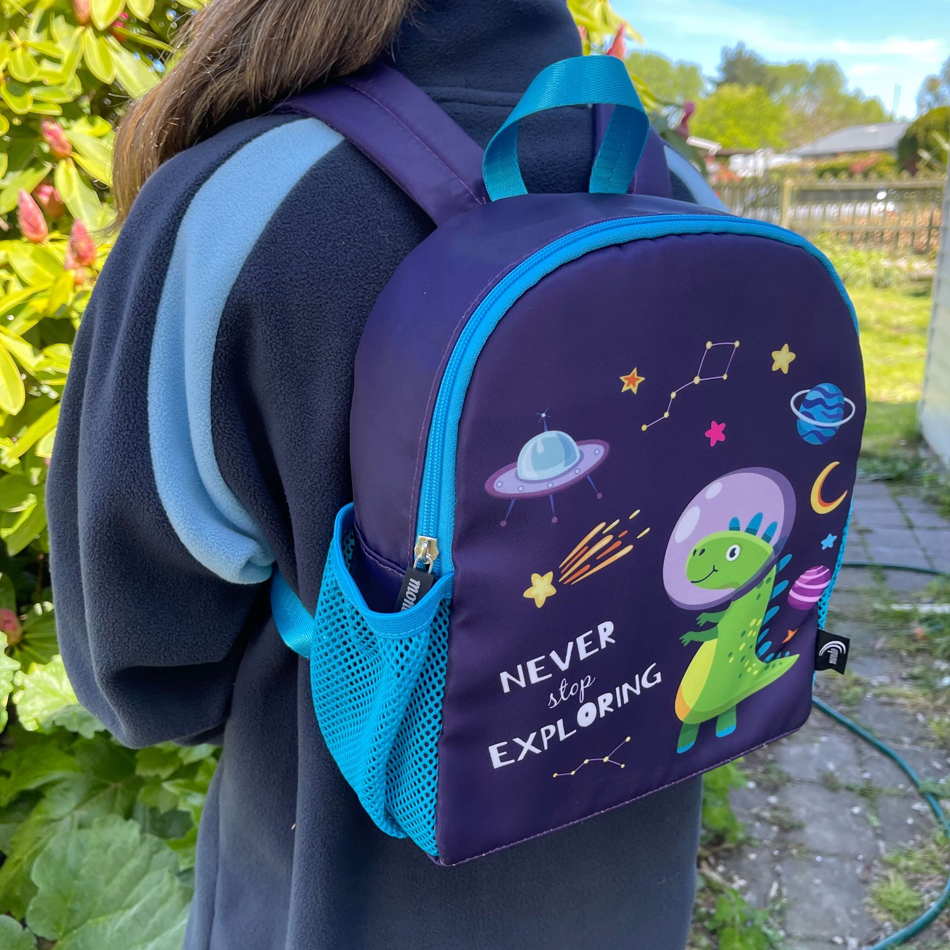 Blue kids backpack with an astronaut dinosaur print and the words "never stop exploring" on it.