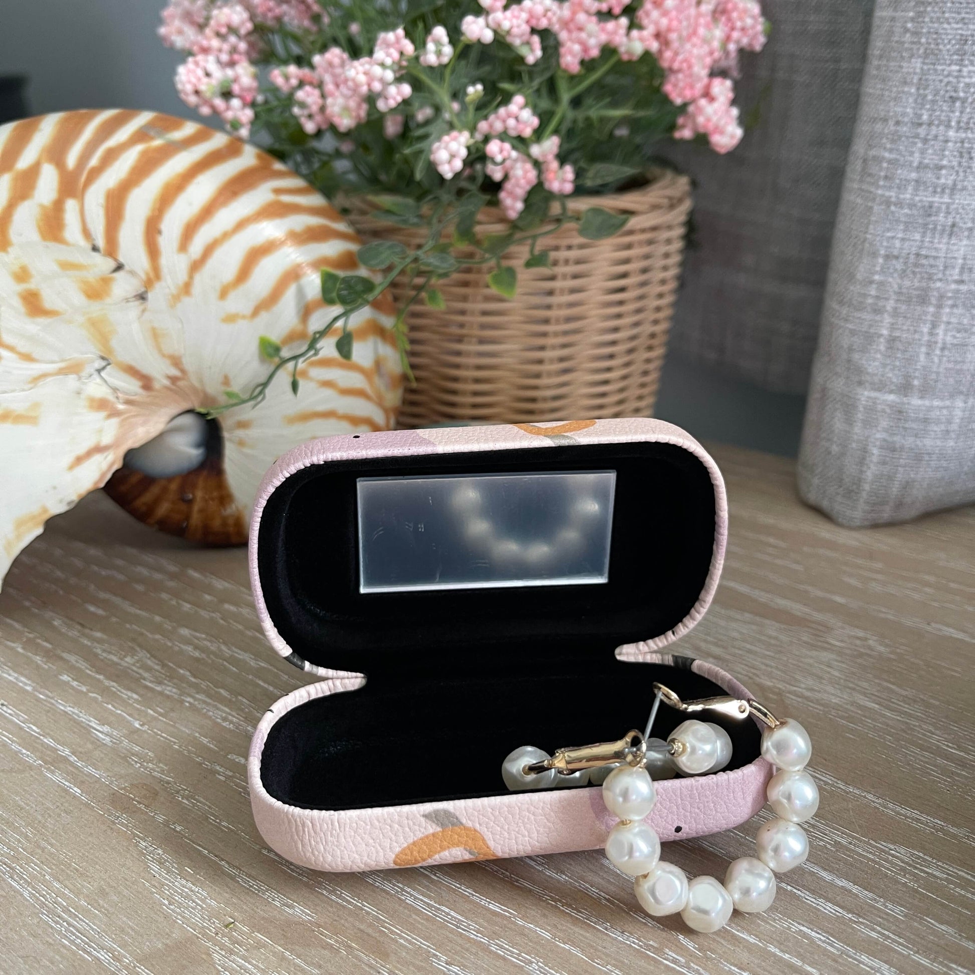 Open trinket case with small mirror and pearl earrings.