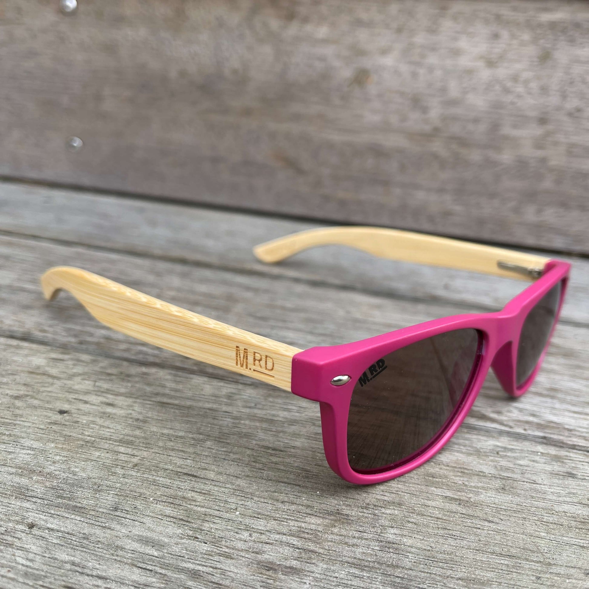 Kids sunglasses with pink frame and wooden arms.