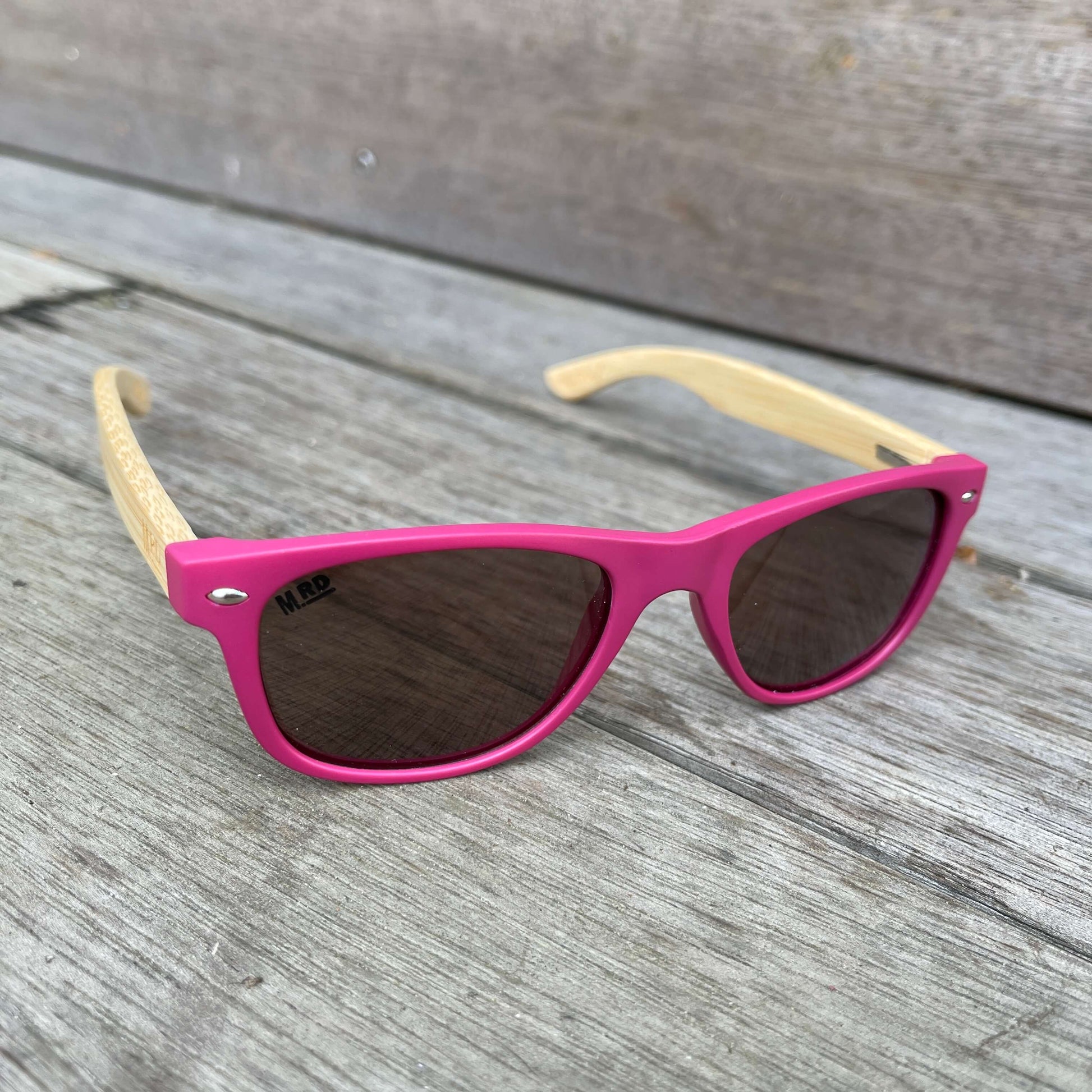 Kids sunglasses with pink frame and wooden arms.