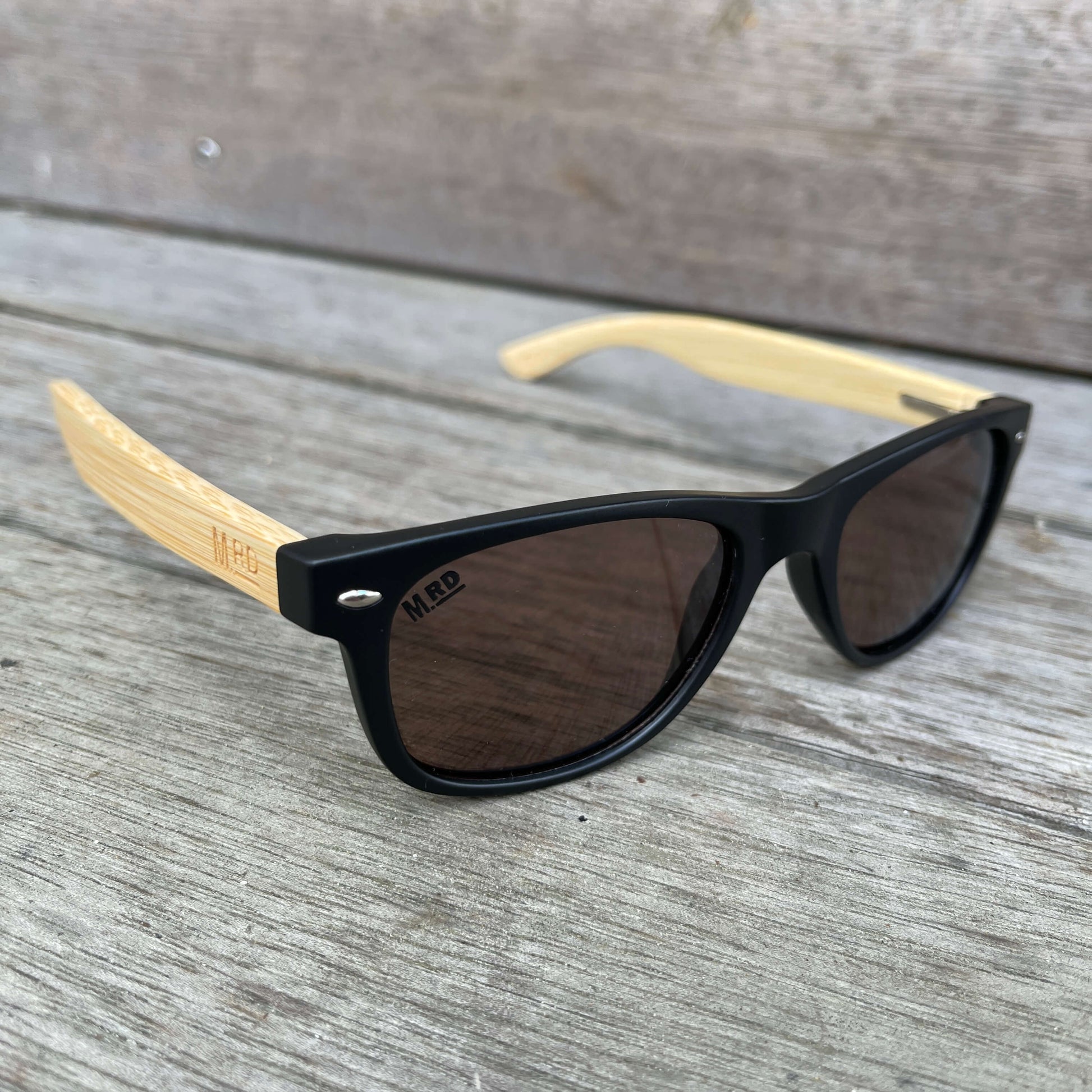 Kids sunglasses with black frame and wood arms.