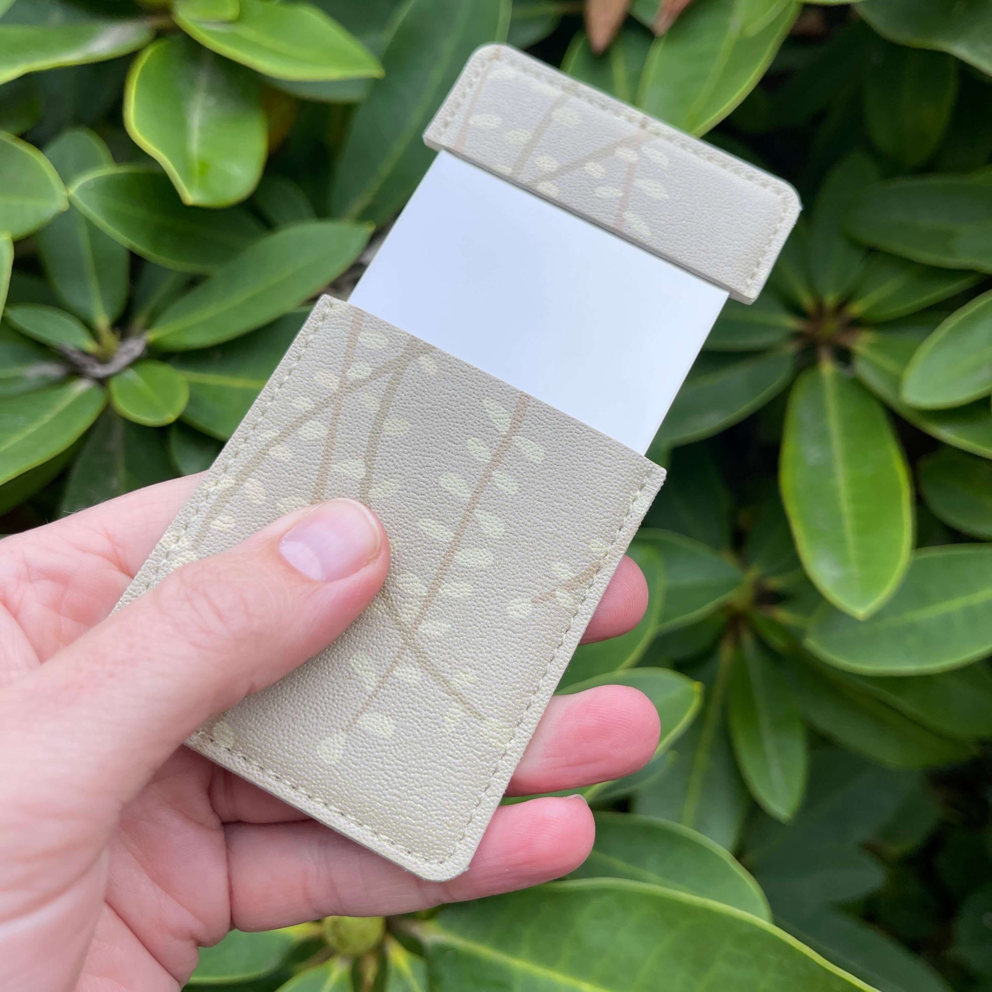 Pocket mirror featuring subtle beige Kowhai leaf against similar background. sini