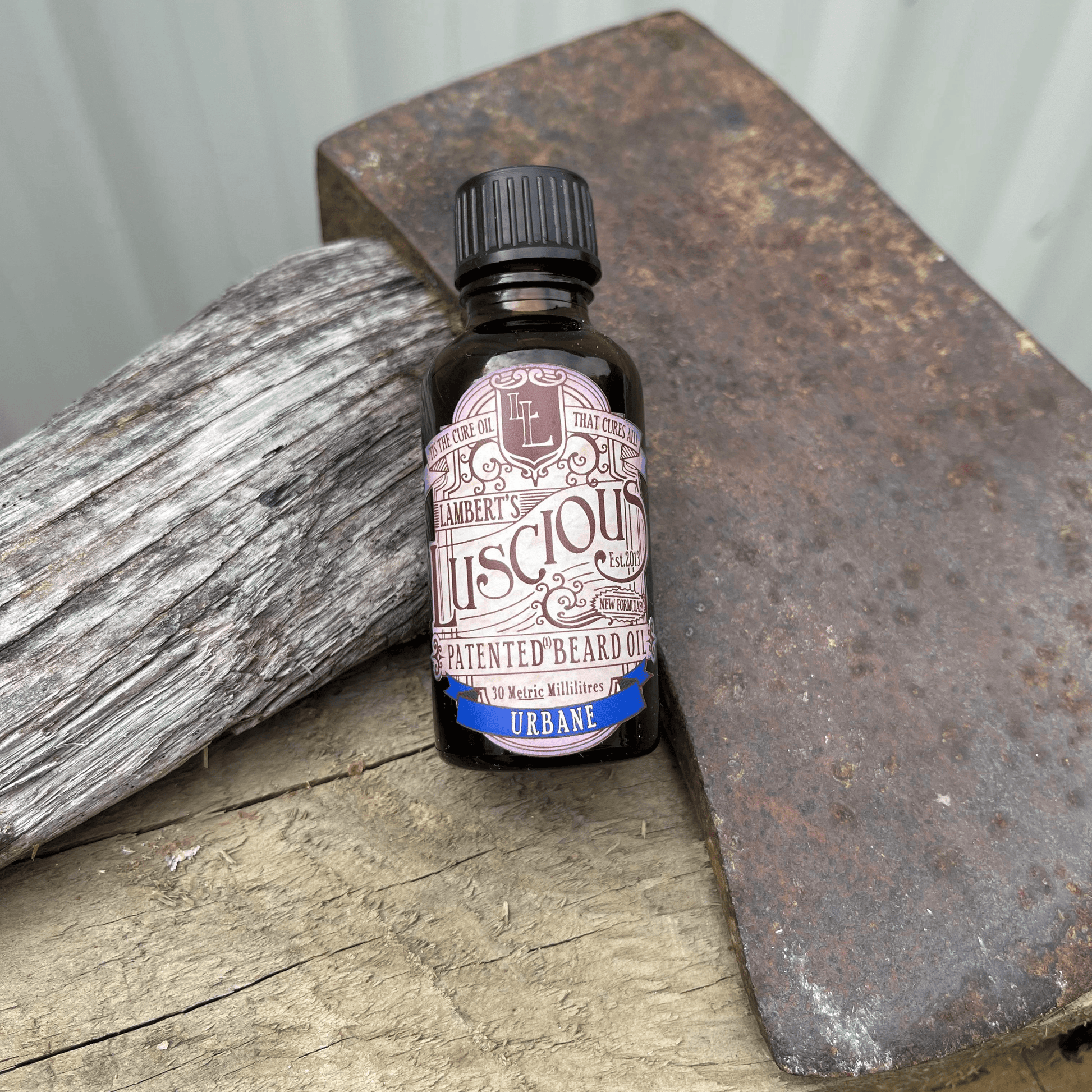 Small bottle of beard oil from Lamberts Luscious resting against an axe blade.