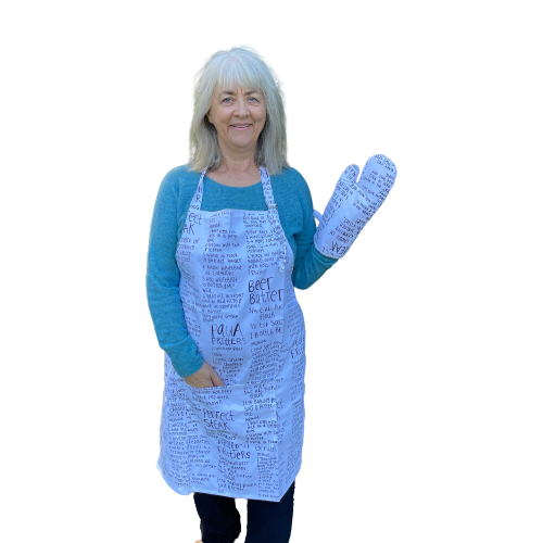 Woman wearing a white apron and mitt set featuring recipes printed on it.