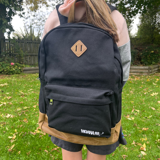 Girl wearing black & tan backpack with 2 zippered compartments.
