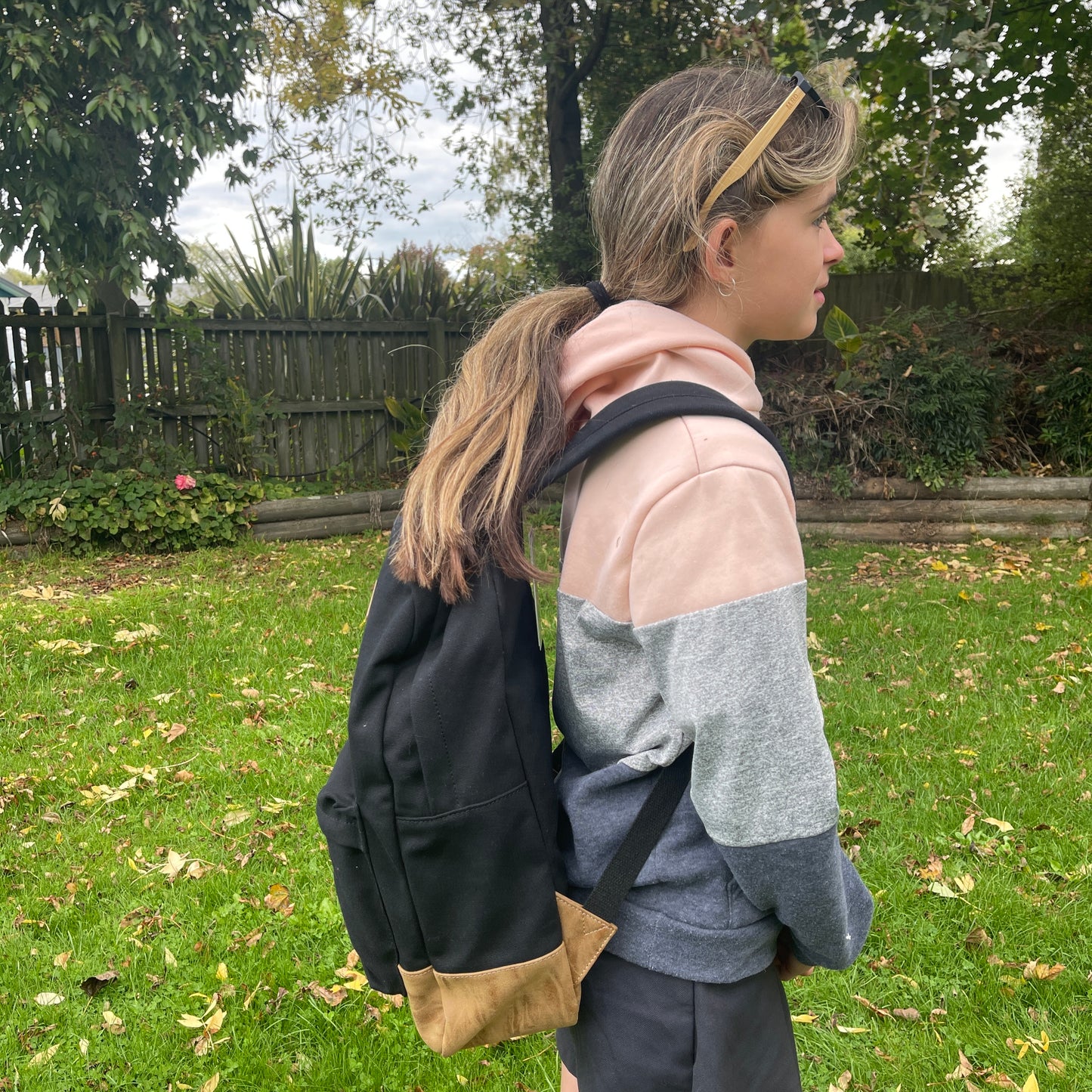 Girl wearing black & tan backpack with 2 zippered compartments.