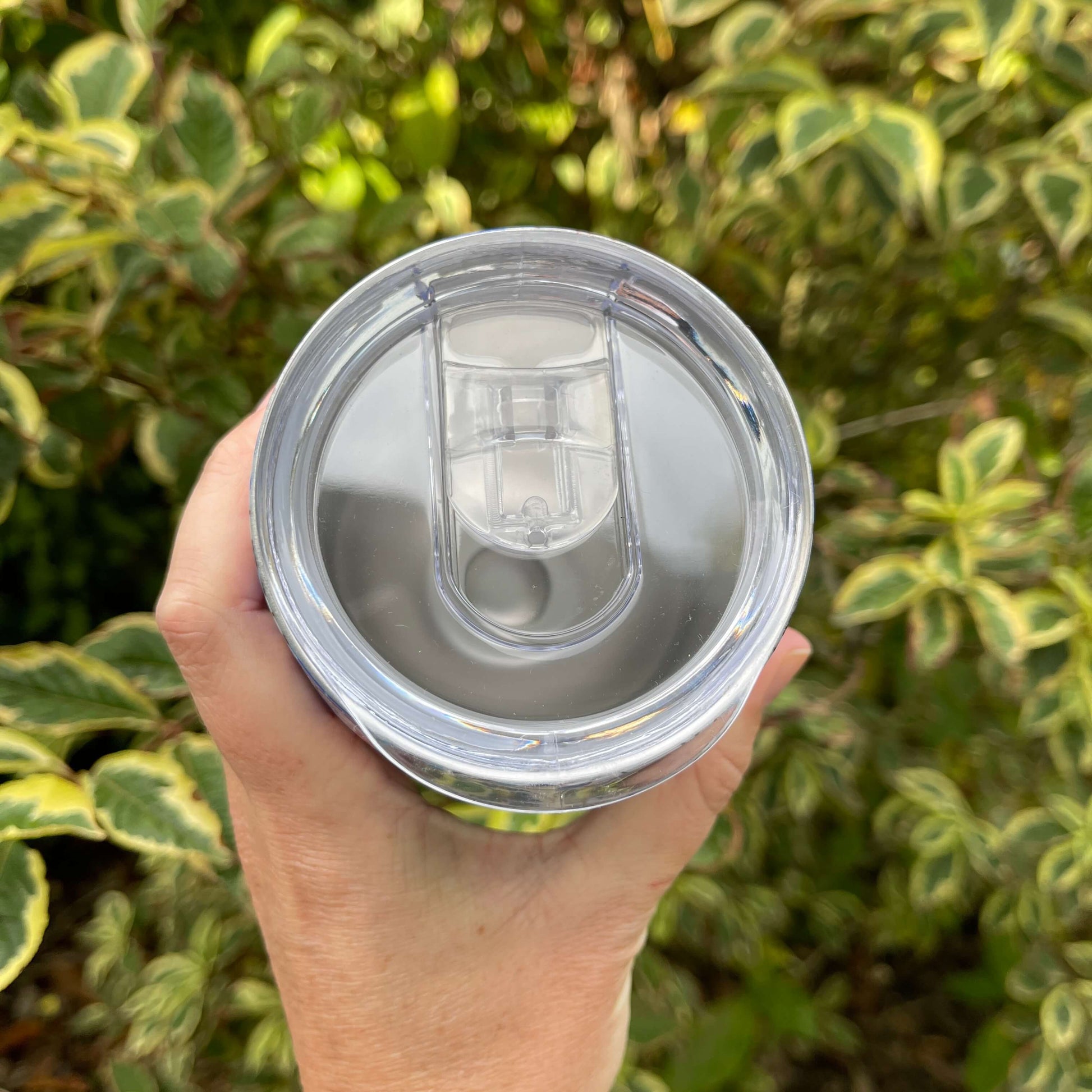 Birds eye view of the top of a reusable coffee mug showing the clear plastic lid.