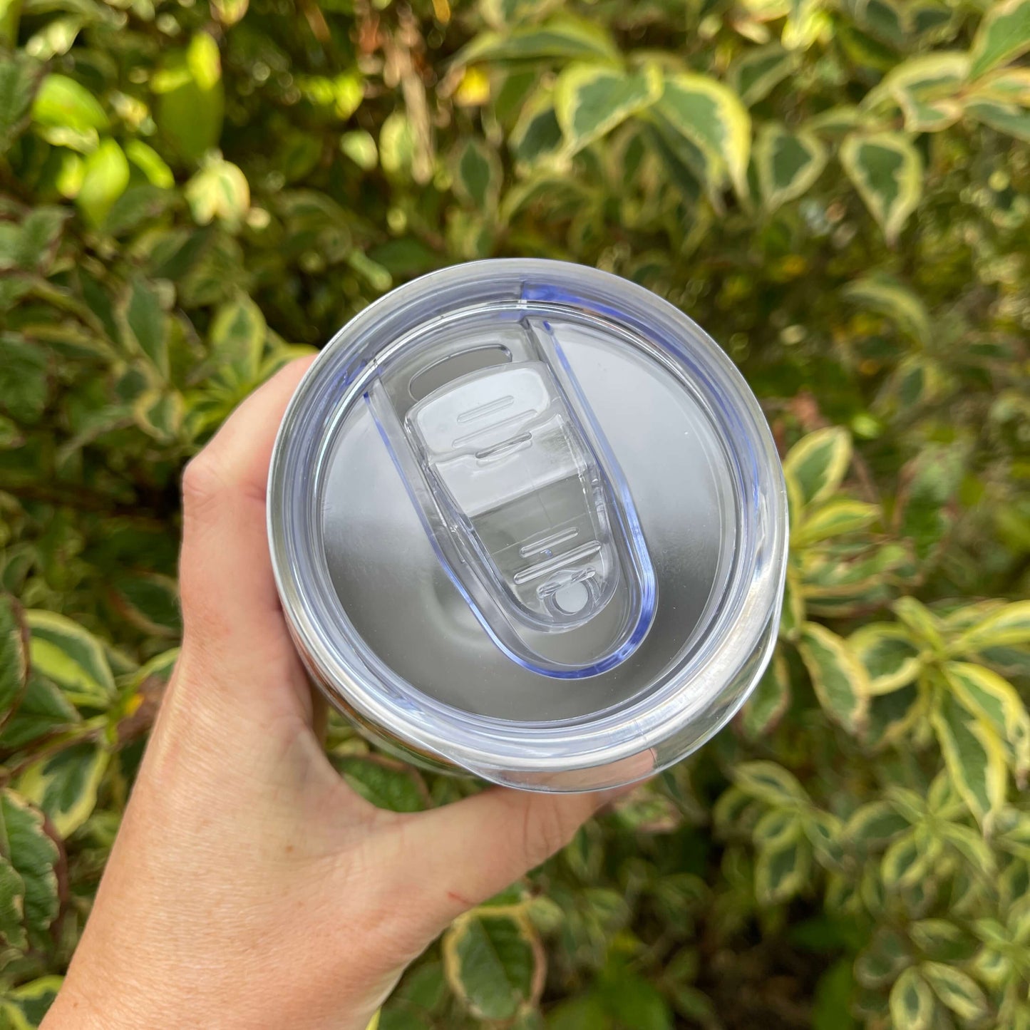 Birds eye view of the top of a reusable coffee mug showing the clear plastic lid.