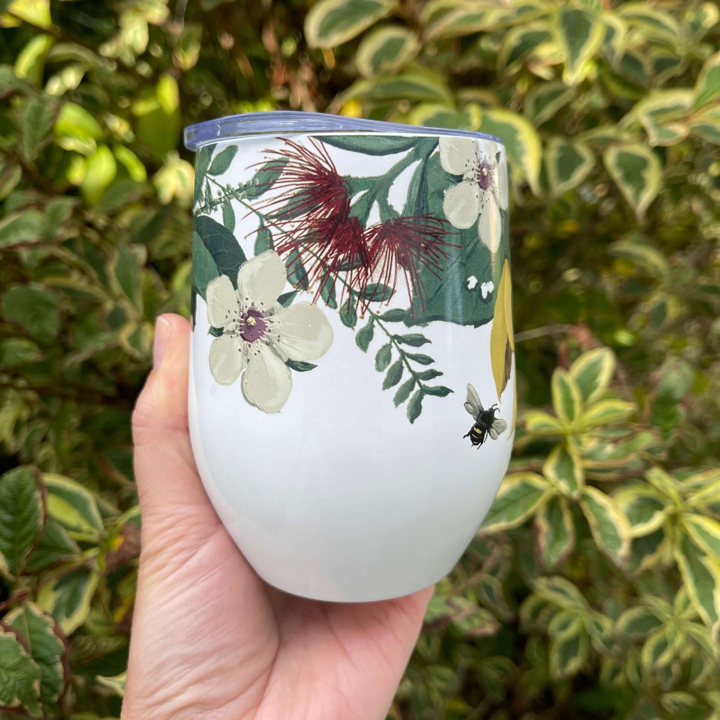 Stainless steel mug painted white with a floral design around the top half of the mug.