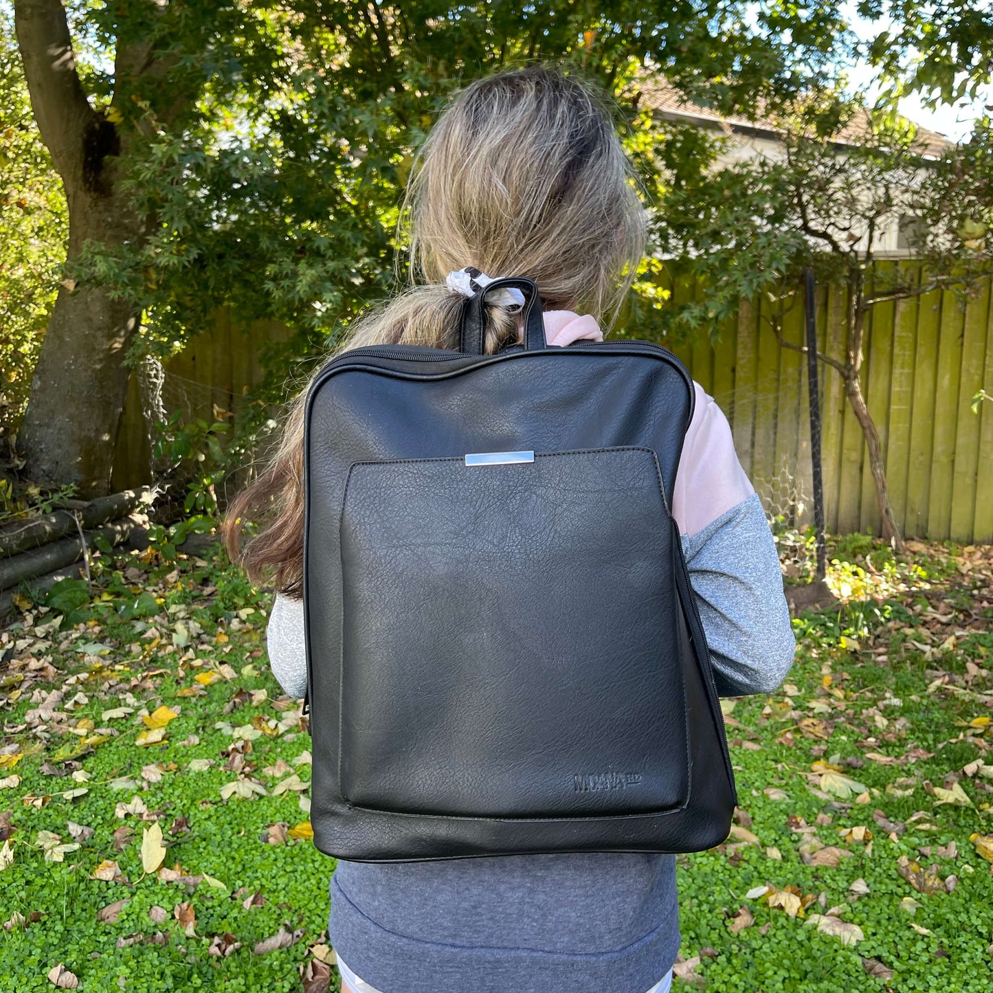 Girl wearing leather look black backpack.