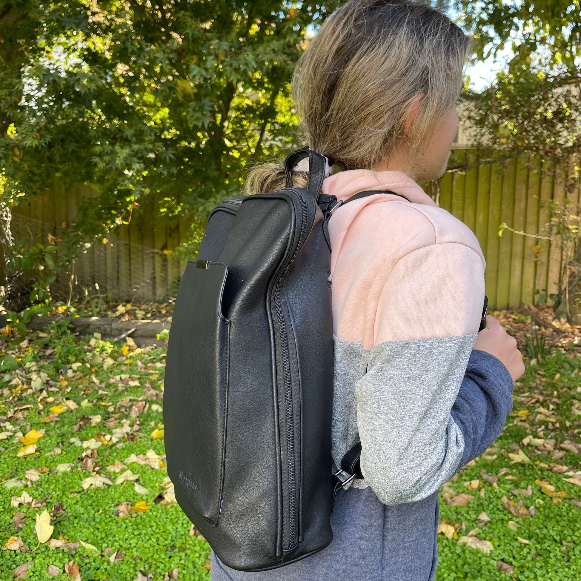 Girl wearing leather look black backpack.