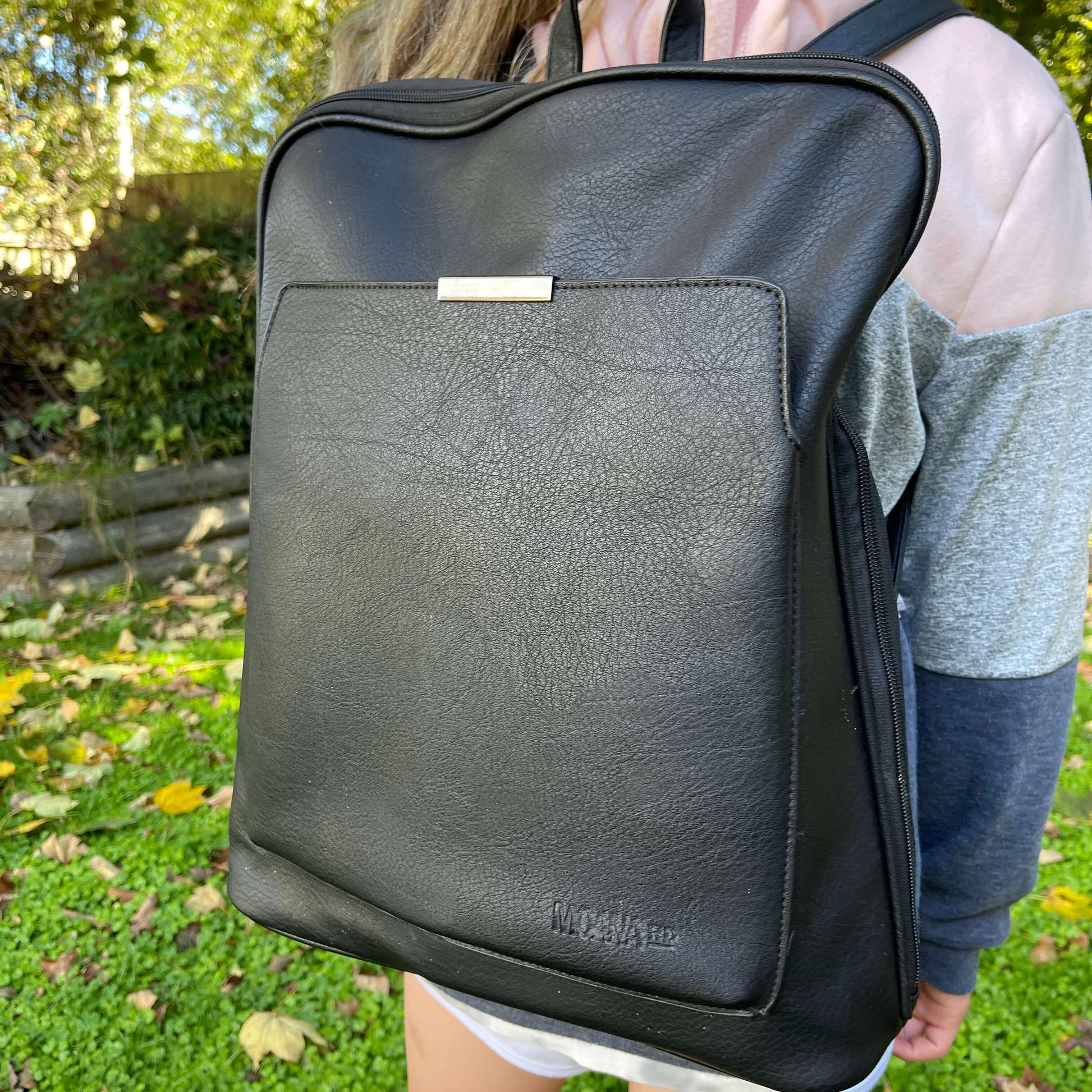 Girl wearing leather look black backpack.