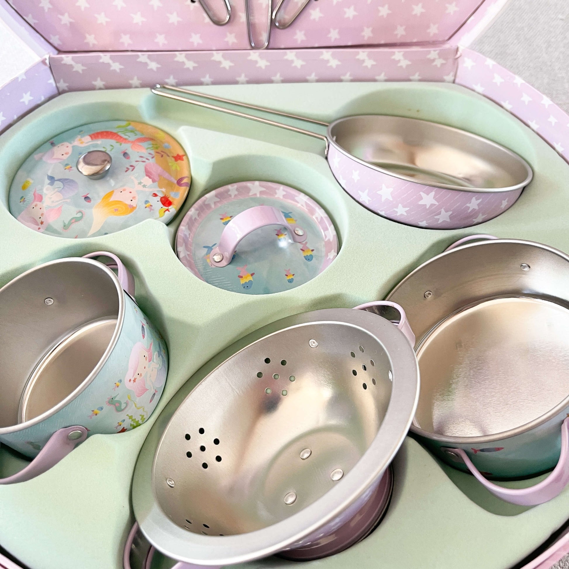 Childrens mermaid themed tin kitchen set close up or pots and pans in the attache case.