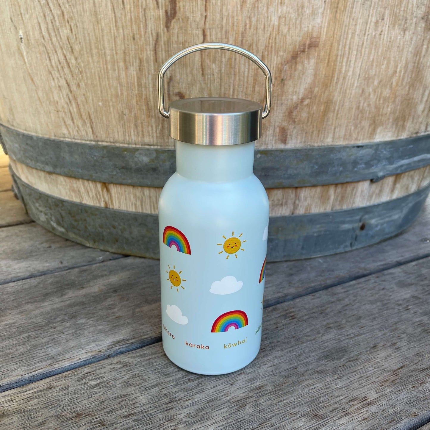 Small kids drink bottle with a stainless screw top in light blue with rainbows, clouds and smiling suns on it.