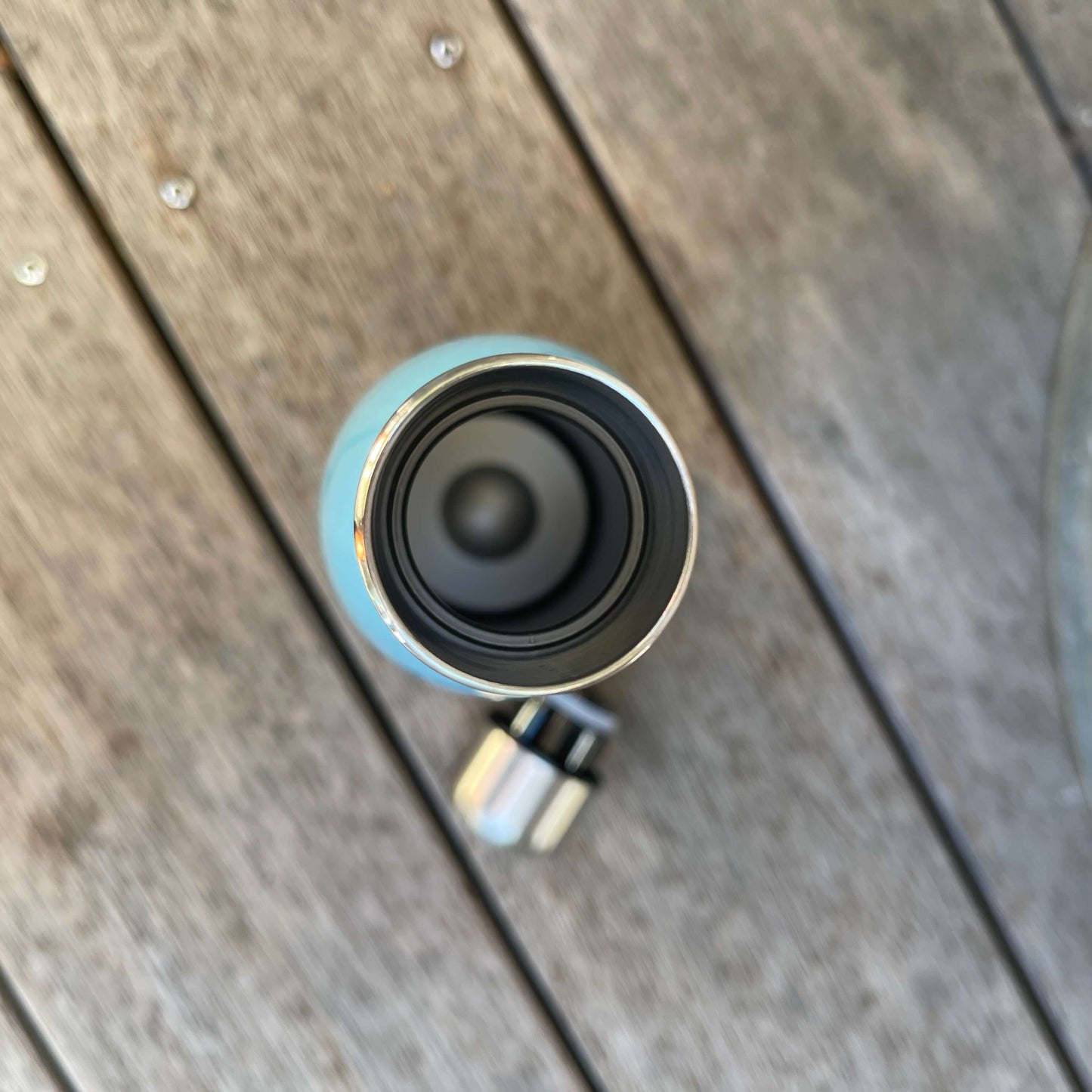 Birds eye view of double wall drink bottle with lid on wooden deck next to it.