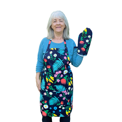 Woman wearing a navy blue and floral apron and mitt set.