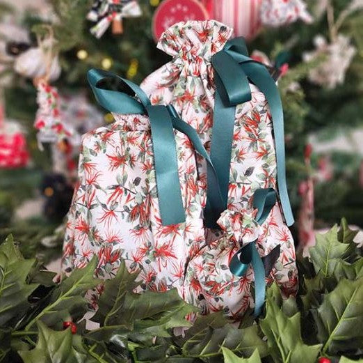 Reusable Christmas gift bags with a native NZ mistletoe print and tied with a green ribbon.